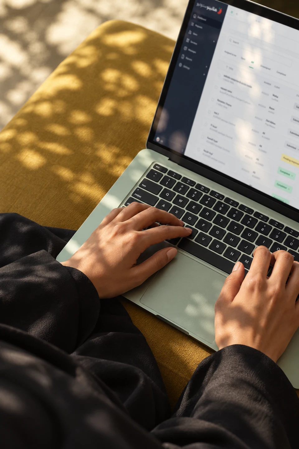Hands using a green laptop in natural daylight